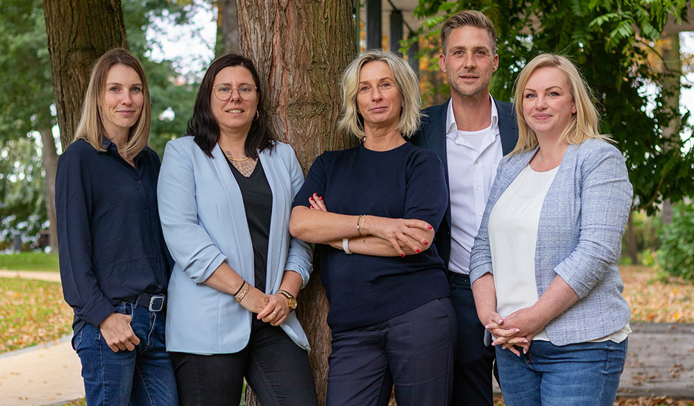 vent immobilien team steht um einen Baum